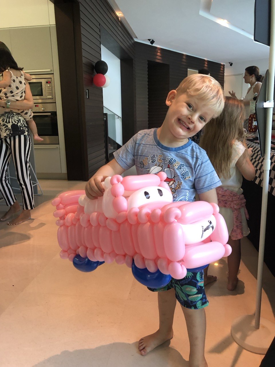Child hugging a pink pig balloon sculpture